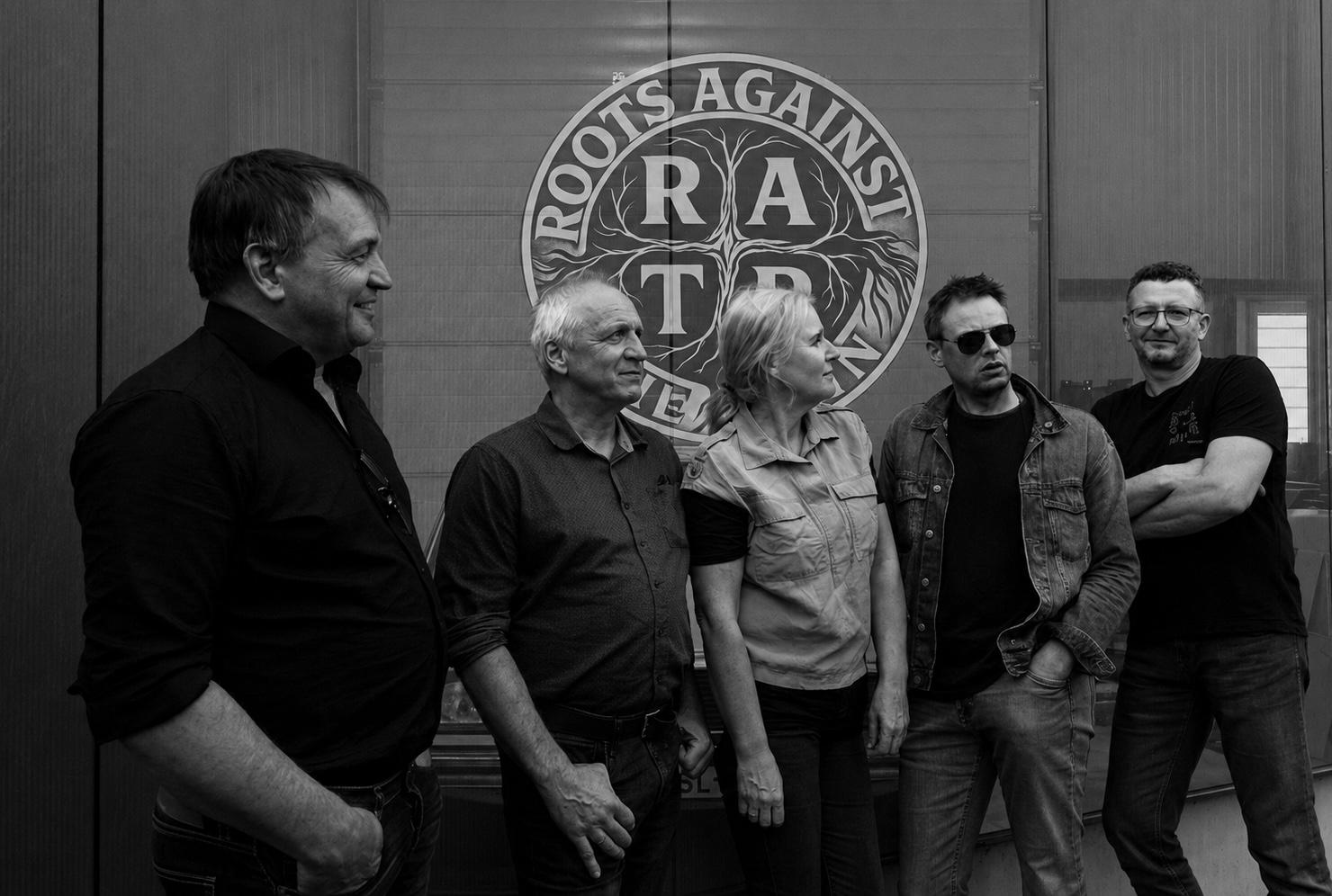 De vijf bandleden voor het logo van Roots Against The Rain